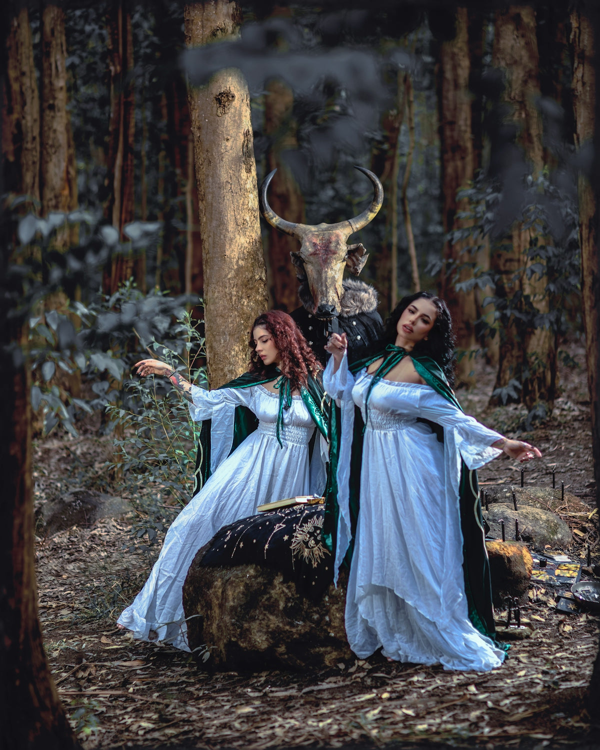 Two women in white dresses and green capes beside a person wearing a bull mask