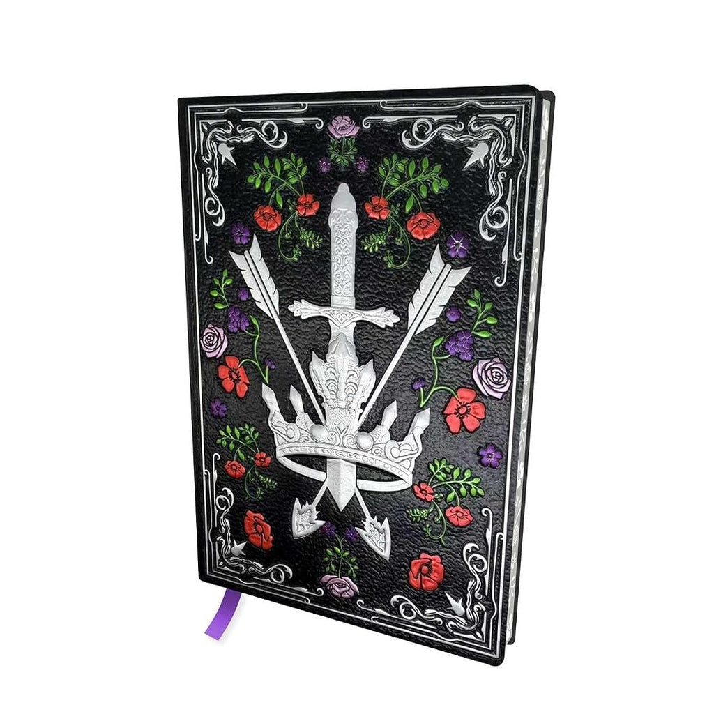 A black hardcover journal featuring a silver engraved dagger and crossed arrows design, surrounded by red and purple flowers and green leaves, with a purple ribbon bookmark hanging from the bottom.