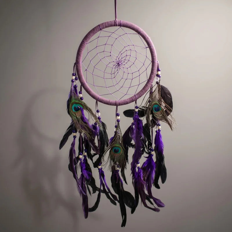 Studio image of purple feather dreamcatcher suspended in mid-air with diffused lighting accentuating stitching and layered feathers.